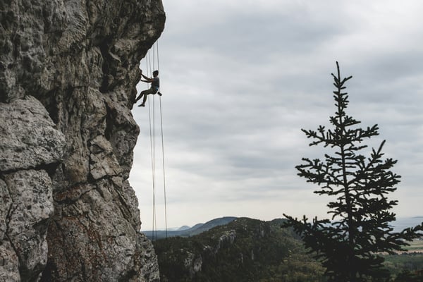 Climber on cliff face with mountains behind
