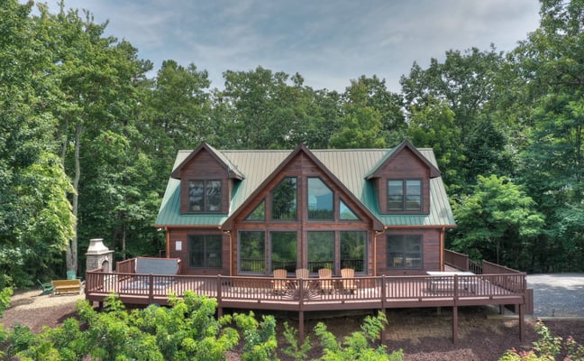 A-frame cabin with green metal roof surrounded by trees